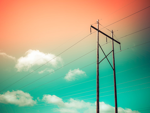 Electric pole and power cables on red and green sky with white clouds backgrounds