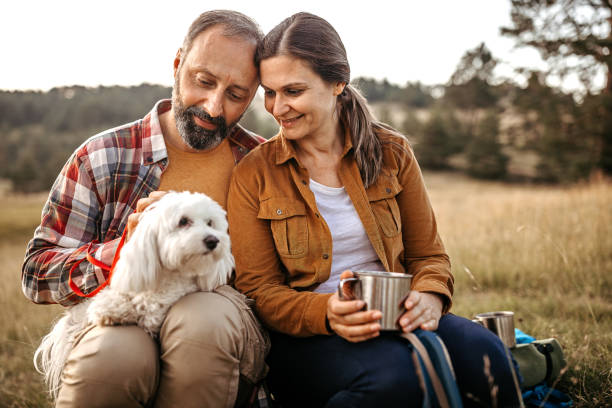 Couple with pet dog relaxing while hiking at forest Happy couple stroking pet dog while relaxing on hiking tour at forest 45 49 years photos stock pictures, royalty-free photos & images