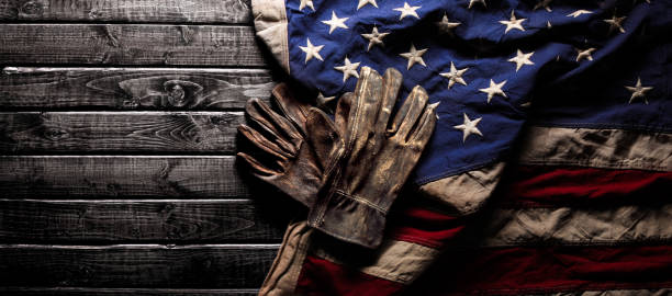 istock Old and worn work gloves on large American flag - Labor day background 1267186135