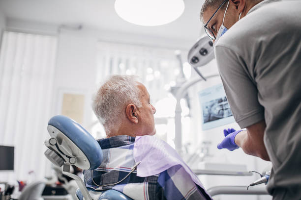 istock Mature male dentist showing teeth problem on dental X-ray 1267186348