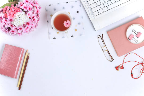 istock Work desk of a modern woman, home office. Notepad, tea, spring flowers  on a light table. Minimal business concept, flat lay, 1267189270