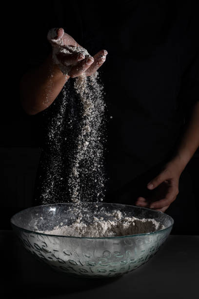 Baker woman hands pulling flour with one hands with a black background