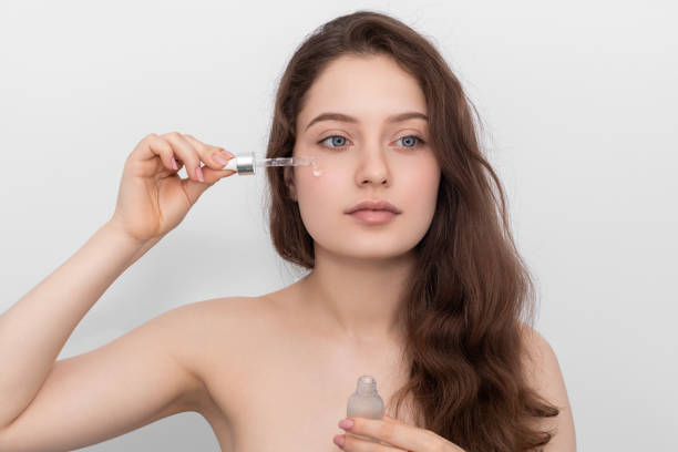 istock Young woman applying serum to her face, looking away. 1267190790