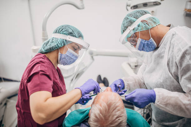 male dentist and his female assistant working at dental office during coronavirus pandemic - dentist dental hygiene dental assistant dentist office imagens e fotografias de stock