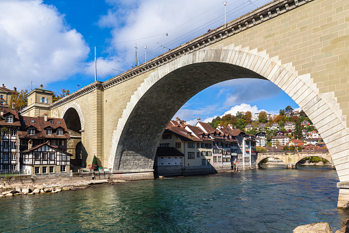 Beautiful view of Bern old town and Aare river under the Nydeggbrücke bridge with Untertorbrücke bridge, on sunny autumn day with blue sky and cloud, Switzerland