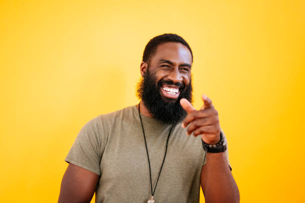 Studio portrait of early 30s black man laughing and pointing