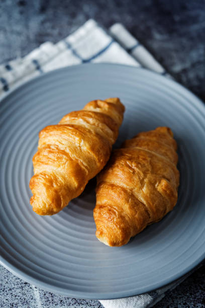 istock Fresh croissants on a plate with cups of coffee 1267200425