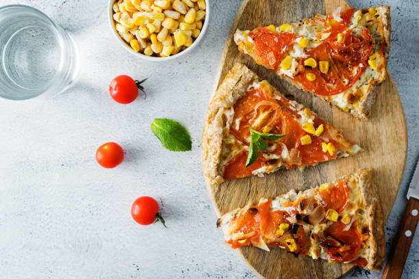 A mouthwatering pizza is showcasing a golden crust topped with melted cheese, sweet corn, and tender pieces of meat, freshly prepared in a cozy kitchen.