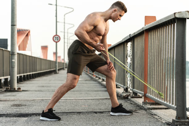 muscular man during workout with a resistance rubber band on a street. - men body building human muscle muscular build imagens e fotografias de stock