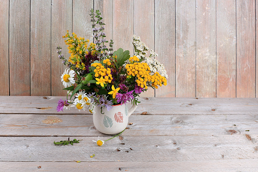 Floral arrangement of wild herbs and flowers on a wooden table, rustic style, autumn background
