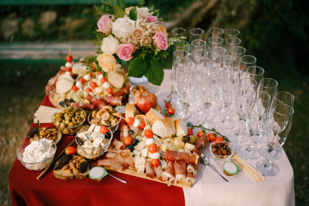 istock Festive table with flowers and clean empty champagne glasses with cheese and cold cuts on a wooden cutting board. 1267203166