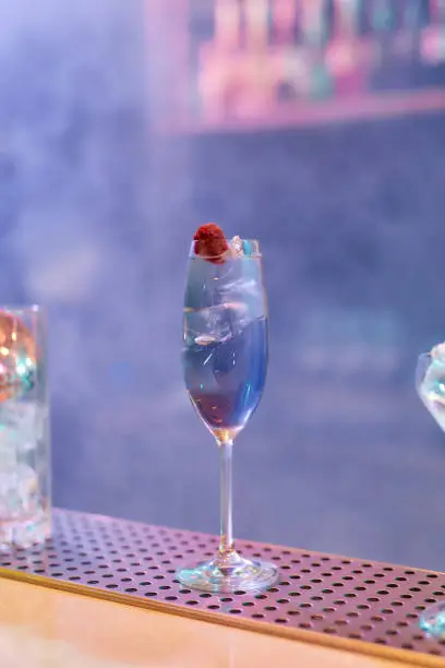 Photo of Good sip for good moments. Close up shot of blue cocktail alcoholic drink on the bar counter in the night club