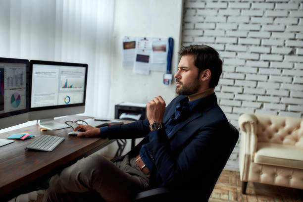 istock Side view of young successful businessman or sales manager analyzing financial data on computer, looking at statistics on pc screen while sitting at his workplace in the modern office 1267206850