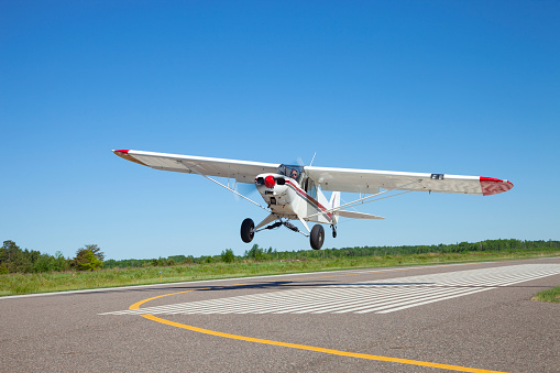 Small white single engine airplane takes off from a municipal airfield in rural Minnesota