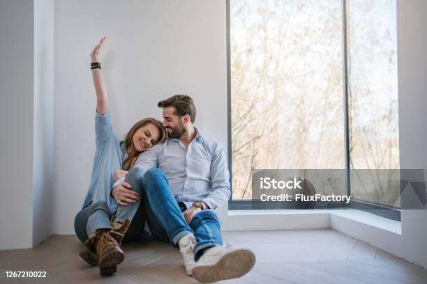 Serene Young Couple Relaxing By The Window In Their New Apartment Stock Photo - Download Image Now