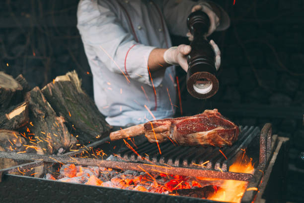 istock Chef Cooking steak. Cook turns the meat on the fire. 1267210582