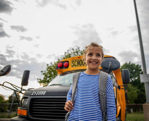 istock Girl in Front of a School Bus 1267213022