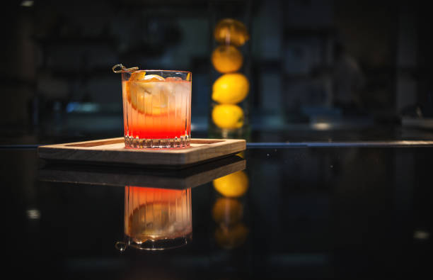 Old Fashioned on The Bar Old fashioned cocktail on the bar, on a wooden tray with lemons in the background. The Old Fashioned is a cocktail made by muddling sugar with bitters, then adding alcohol, such as whiskey or brandy, and a twist of citrus rind cocktail stock pictures, royalty-free photos & images