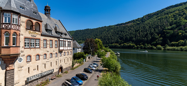 Traben-Trarbach, Rheinland-Pfalz / Germany - 31 July 2020: view of the historic post office in Traben-Trarbach and the Mosel River with a boat headed upstream