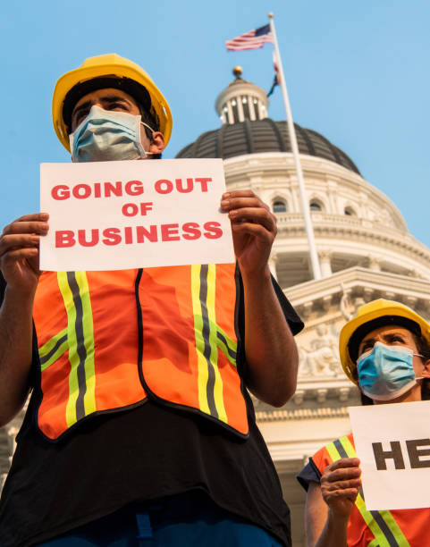 istock Construction workers demonstrating outside a government building wearing protective face mask holding help and going out of business signs 1267217091