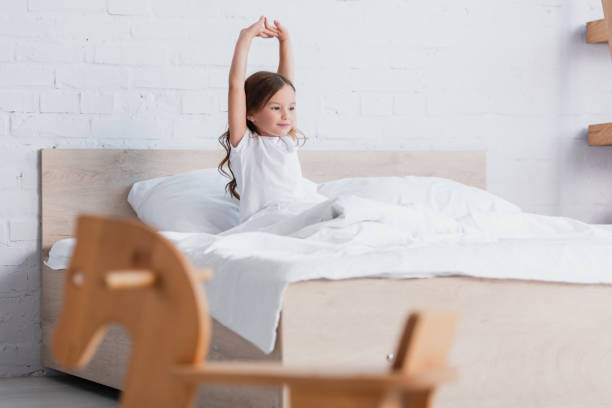 istock selective focus of awakened kid stretching while sitting in bed 1267217181