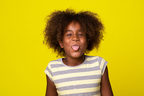 Studio portrait of a happy, playful girl sticking tongue out and having fun.