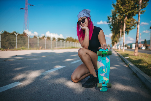 A young woman with a skateboard in her hands outdoors