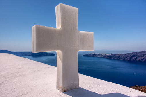 This cross on a church in Greece overlooks the blue sea.