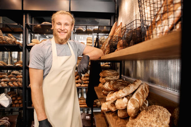 istock Small Business.Bearded man assistant standing at bakery shop leaning on shelf with bread posing to camera smiling cheerful 1267229067
