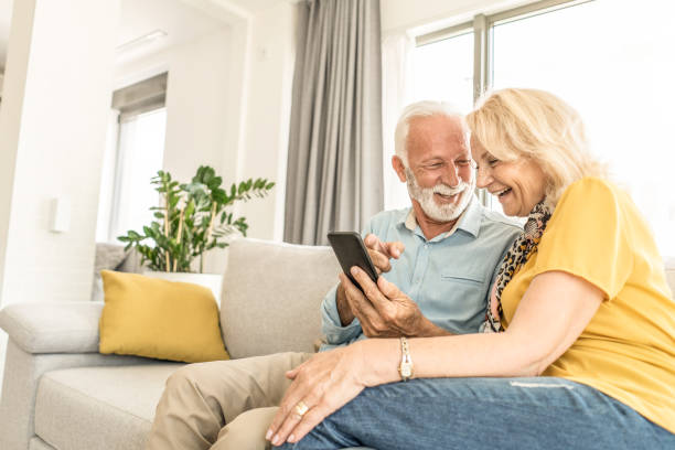 istock Happy senior couple using phone on sofa. 1267232980