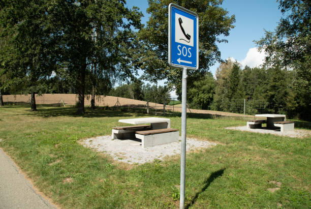 motorway rest area with tables and benches, in the foreground there is a blue s.o.s. sign with a black telephone, safety at such places is very important so that people can rest without fear, in case of an accident rescue services are immediately available by telephone, during the day, no persons zona de descanso de la autopista con mesas y bancos, en primer plano hay un letrero azul s.o.s. con un teléfono negro, la seguridad en tales lugares es muy importante para que la gente pueda descansar sin miedo, en caso de un accidente los servicios de re
