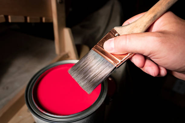 Handheld paintbrush and red paint stock photo