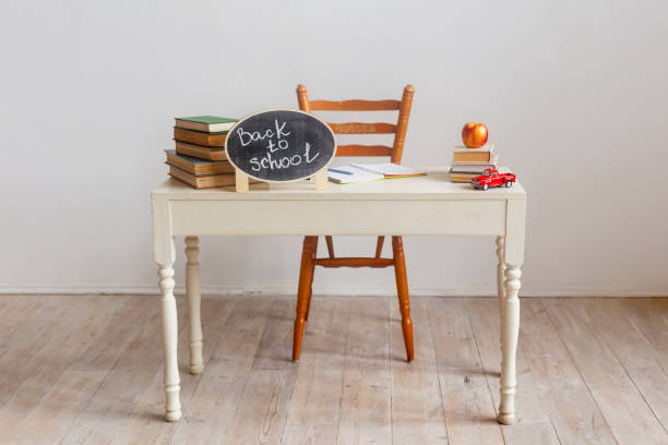istock School desk with textbooks. Stack of books on white table with red apple. Back to school 1267242340