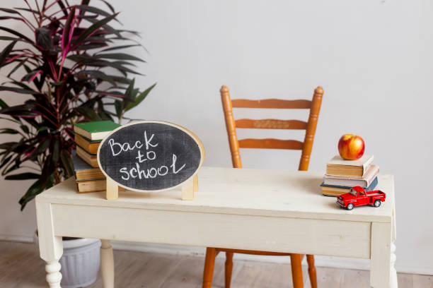 istock School desk with textbooks. Stack of books on white table with red apple. Back to school 1267242344