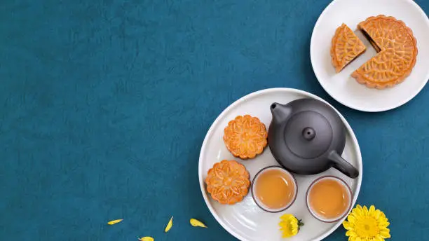 Photo of Moon cake for Mid-Autumn Festival, delicious beautiful fresh mooncake on a plate over blue background table, top view, flat lay layout design concept.