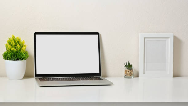 istock Mock up stylish of workspace with blank screen laptop, tree, frame picture and cactus on white table and white background. Front view. 1267250151