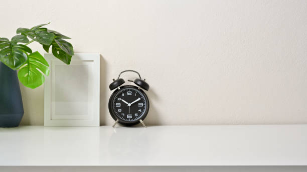 istock Modern decor workspace with frame pictures, clock and vase on white table and white background. Front view. 1267250156