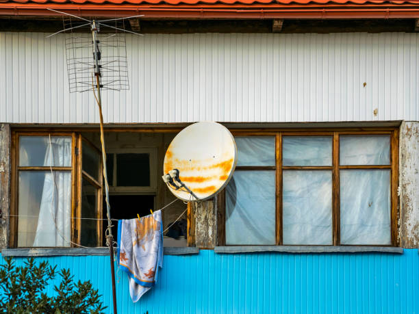Satellite dish at the roof of country house with mountain background for internet, television and communication connection in rural countryside area.