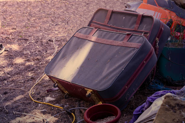 Dirty old weathered broken suitcases discarded and abandoned among other junk, processed in a retro style tone.