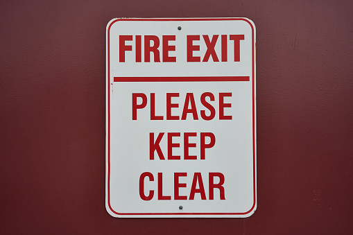 Fire exit sign isolated on a dark red background.