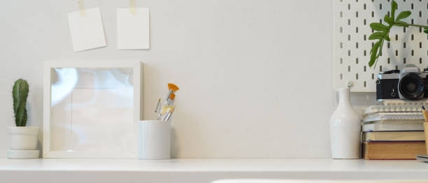 istock Workplace with copy space, books, camera, paint brushes and decorations on white table 1267267038