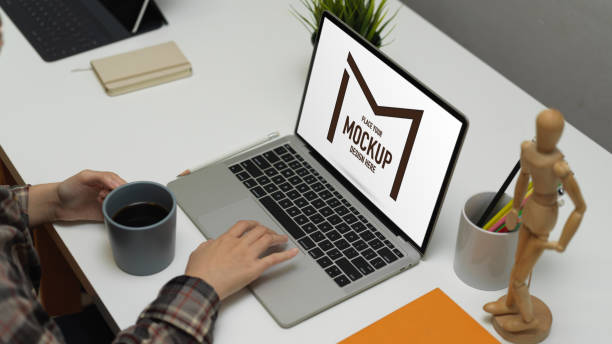 istock Cropped shot of female working with mock up laptop while holding coffee cup on worktable 1267268293