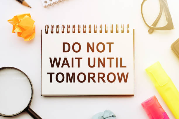 istock Writing a note that says Do not wait until tomorrow. Urgently better to do it now. Copy space on blank note paper with markers, magnifier, glasses and crumpled paper 1267270637