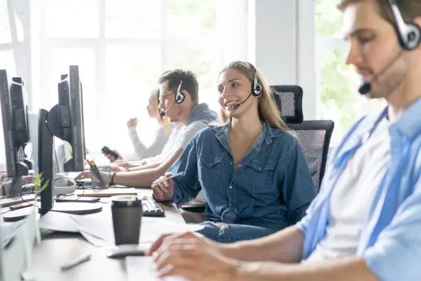 Young handsome male customer support phone operator with headset working in call center.
