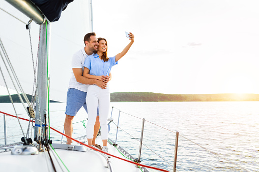 Sailing Adventure Concept. Lovely Couple Standing On Yacht Making Selfie During Boat Tour In Sea. Empty Space For Text