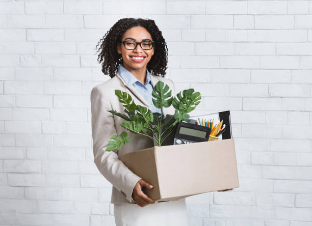 Portrait of happy black businesswoman with box of belongings starting new job at office Portrait of smiling black businesswoman with box of belongings starting new job at office belongings stock pictures, royalty-free photos & images