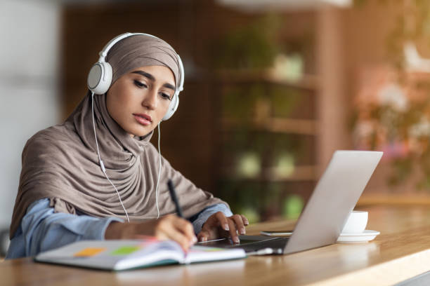 flicka i huvudduk med online lektion på laptop på café - anständig klädsel bildbanksfoton och bilder