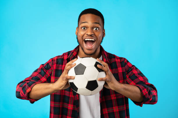 istock Emotional Black Guy Shouting Holding Soccer Ball On Blue Background 1267272182