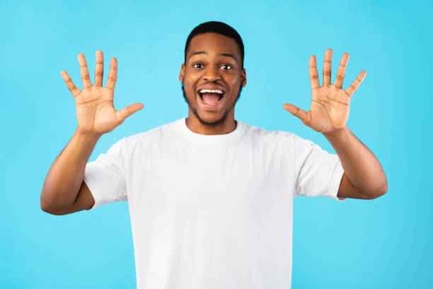 Joyful Black Man Showing Number Ten Over Blue Background Joyful Black Man Showing Number Ten With Both Hands Smiling To Camera Posing Over Blue Background. Studio Shot number 10 sign stock pictures, royalty-free photos & images