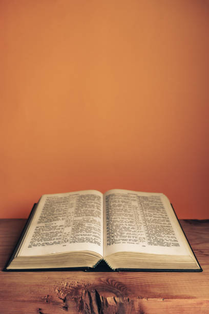 istock Open Holy Bible on a old wooden table. Beautiful orange wall background. 1267274685